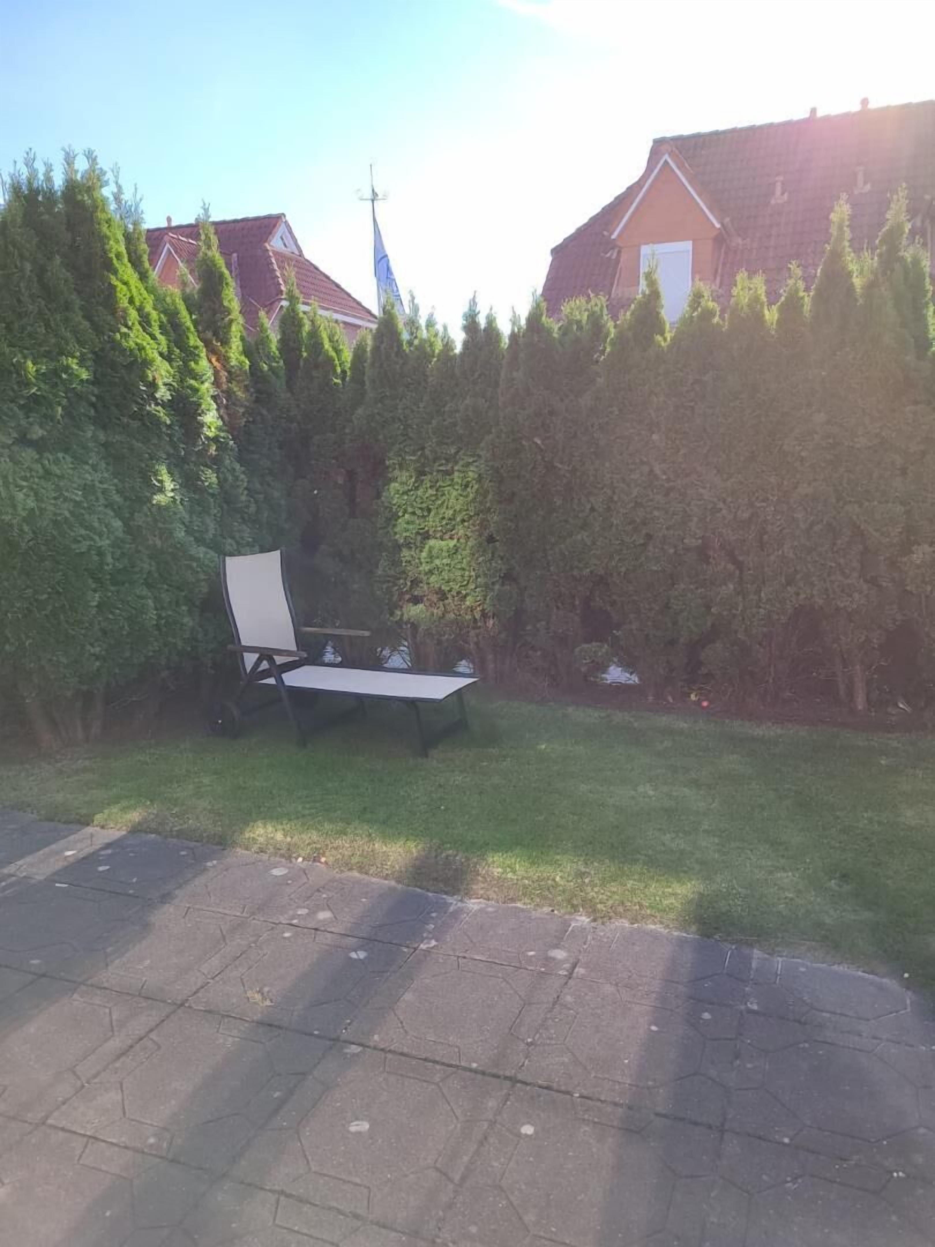 A backyard with a lawn, a metal table, and a metal chair. There are houses in the background.