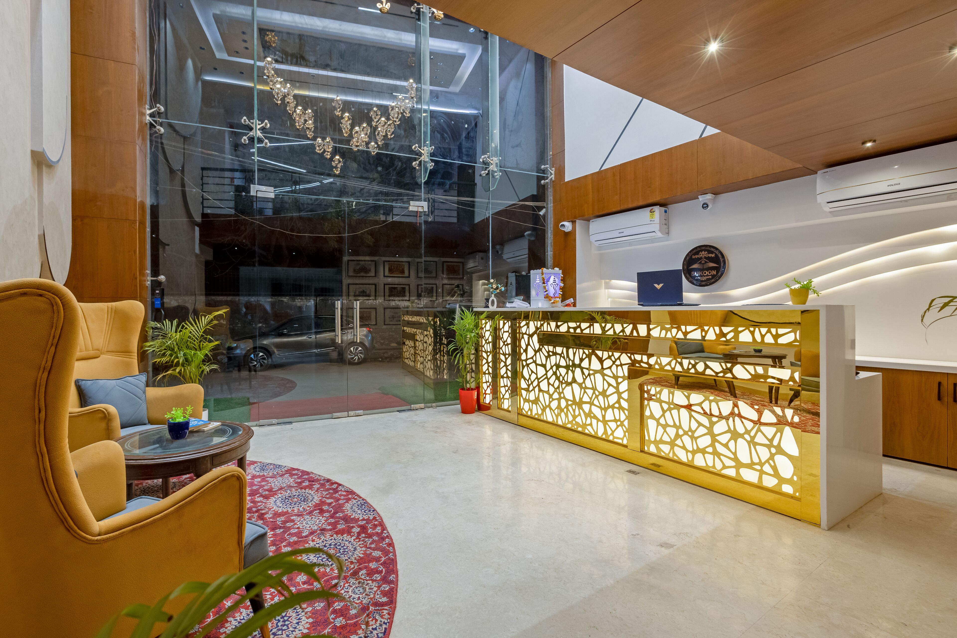 A modern reception area with a glass wall, wooden reception desk, and comfortable seating.
