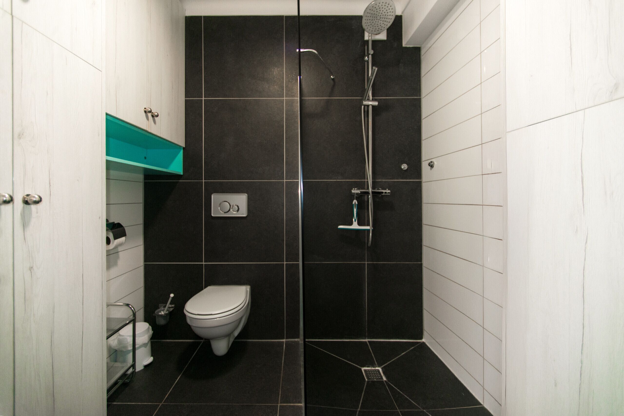 Une petite salle de bain moderne, équipée de toilettes, d’une douche et d’un lavabo.