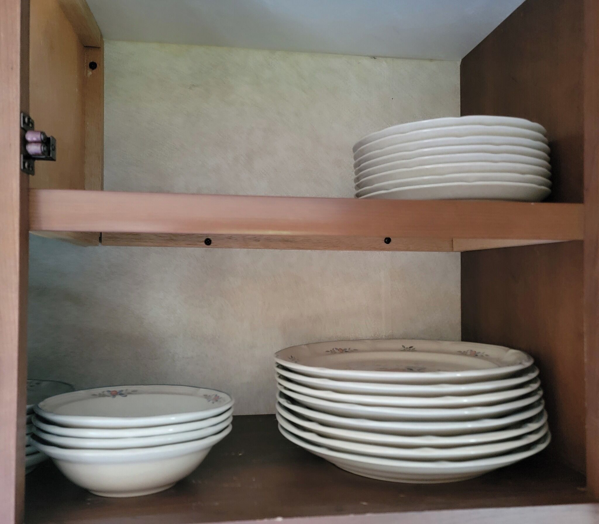 A storage cabinet with shelves holding stacked plates and bowls.
