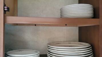 A storage cabinet with shelves holding stacked plates and bowls.
