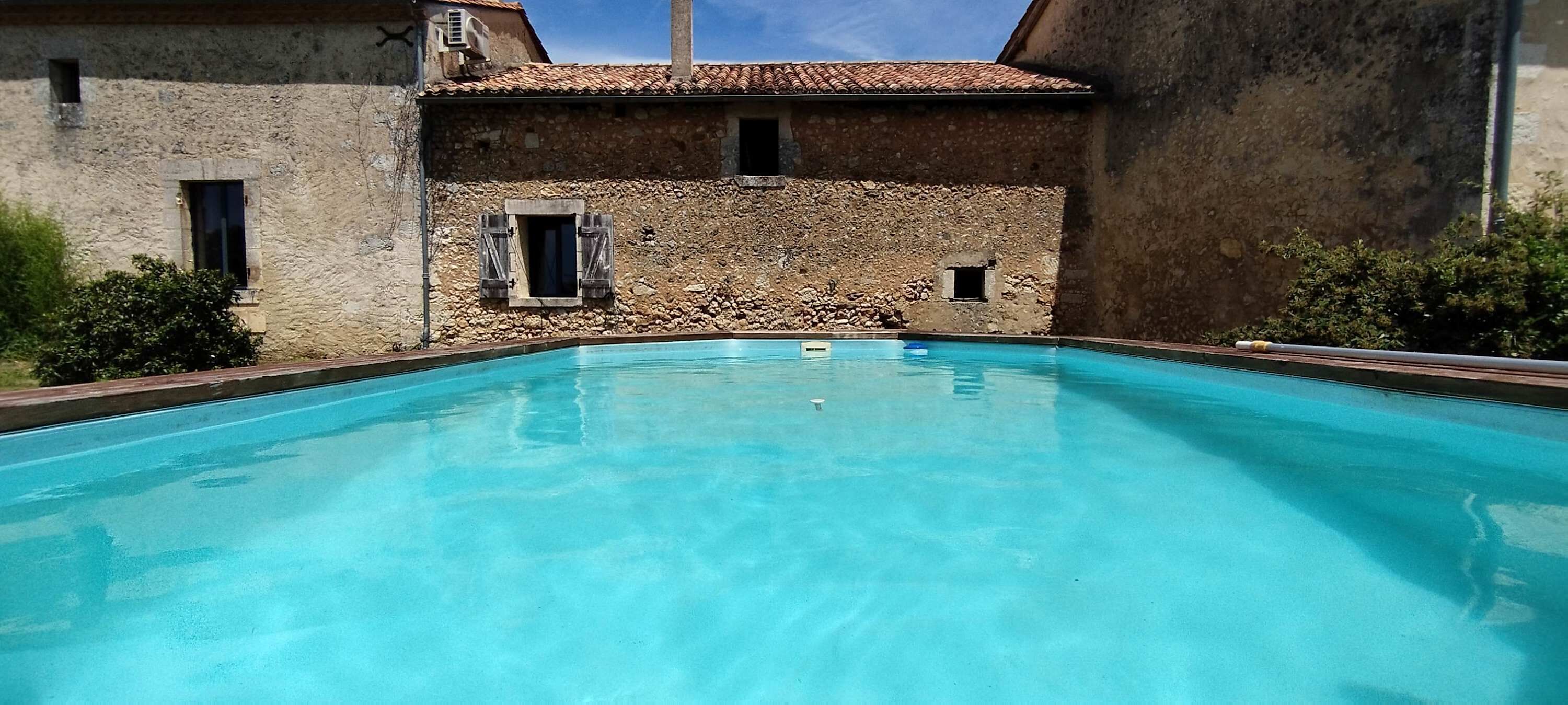 A clear swimming pool with stone walls and a tiled roof.