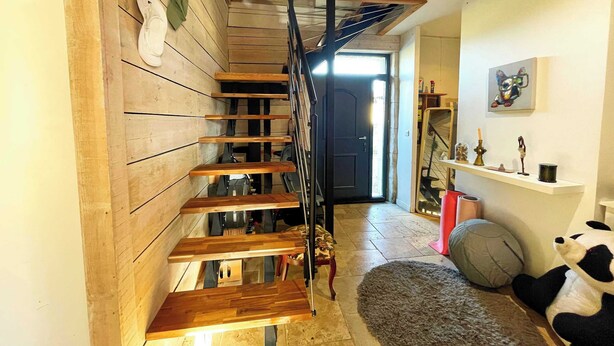 A wooden staircase with a black metal railing leading to an upper level.