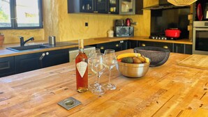 A wooden kitchen island with a bottle of wine, glasses, and a bowl of fruit.