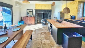 A modern kitchen with a central island, a dining area with a bench, and a fireplace.