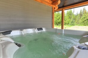 A hot tub with a view of a forested area. - Cabin # 2 - Lakeside cabin sleeps 11 with private hot tub (Naramata)