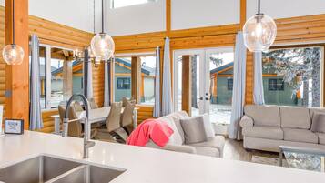 Un intérieur moderne comprenant un espace cuisine, un coin repas et un salon avec de grandes fenêtres.