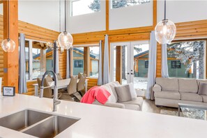 Un interior moderno con cocina, comedor y zona de estar, con amplios ventanales.