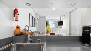 A modern kitchen with a stainless steel sink, a Keurig coffee maker, and a fire extinguisher on the wall. - Condado del Mar by Otium (San Juan)