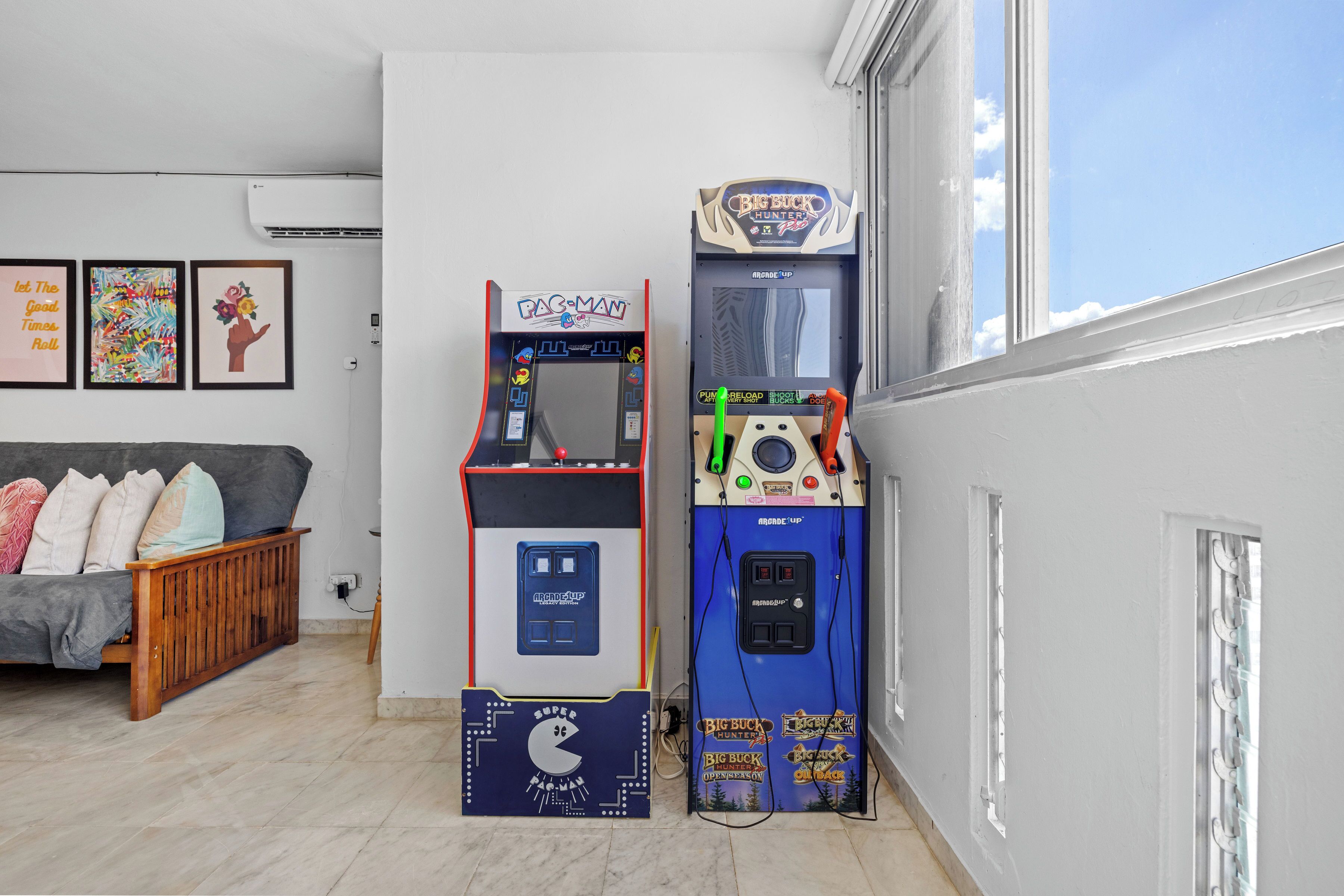 Una habitación con una cama, un sofá y dos máquinas de videojuegos.