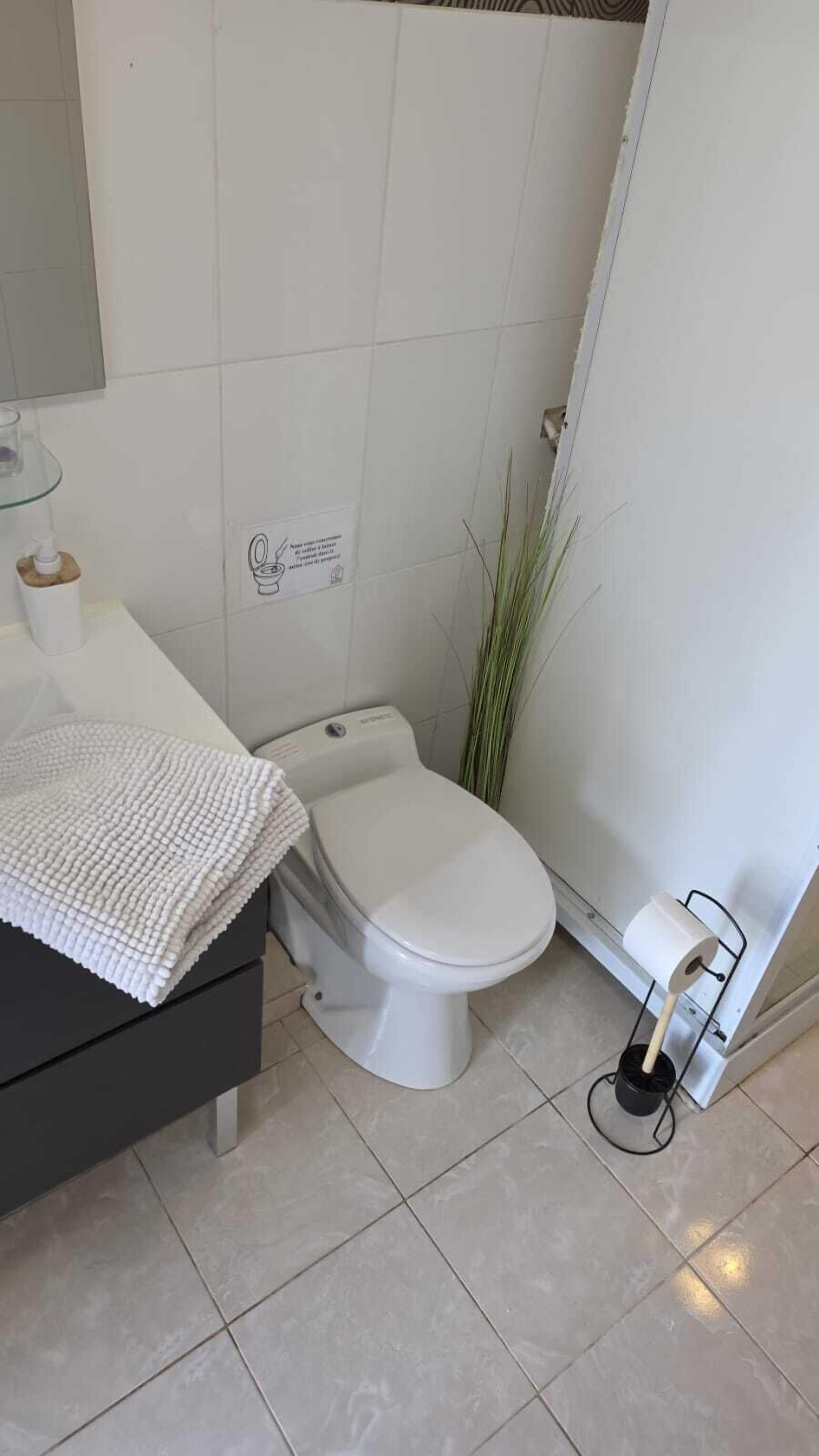 Une salle de bain comprenant des toilettes, un lavabo avec une serviette et un espace douche.
