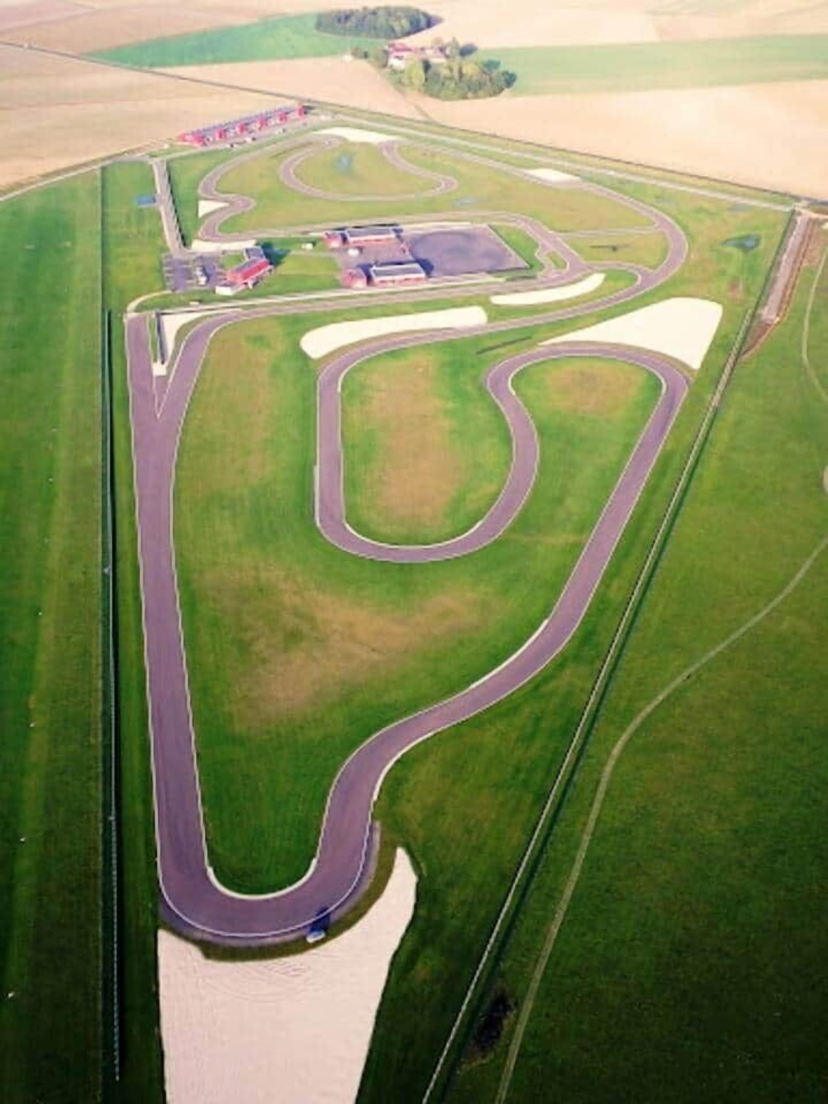 An aerial view of a racetrack with multiple curves and a large water body.