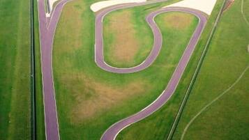 An aerial view of a racetrack with multiple curves and a large water body.