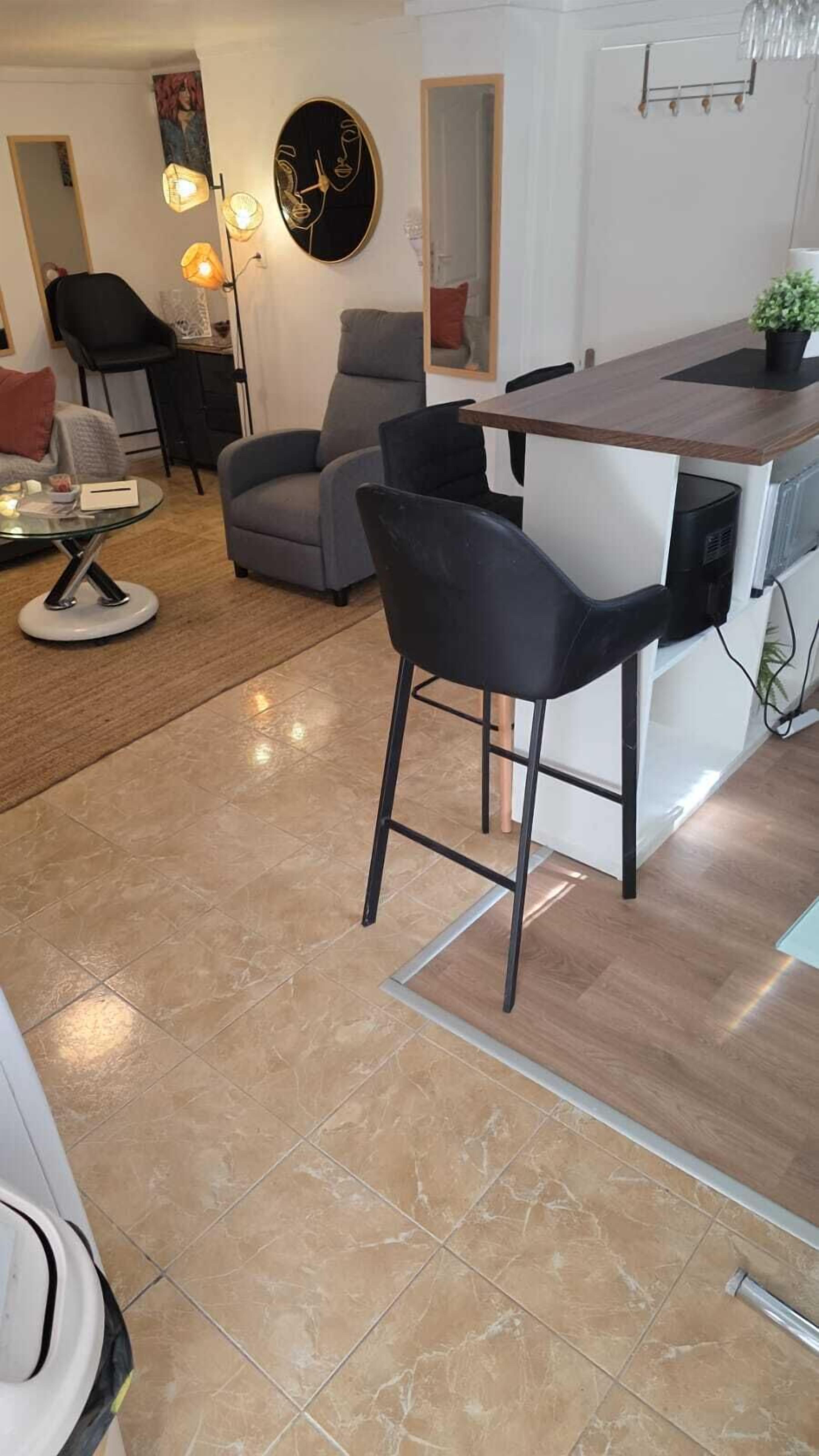 Uma cozinha moderna com área de bar, mesa de jantar e sala de estar com sofá e cadeiras.