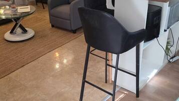 Uma cozinha moderna com área de bar, mesa de jantar e sala de estar com sofá e cadeiras.