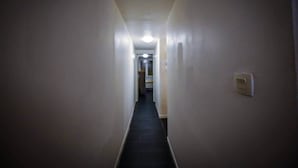 A narrow, dimly lit hallway with plain walls and a light switch on the right.