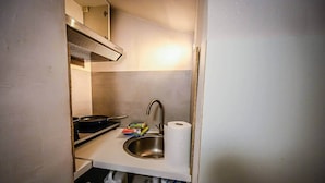 A compact kitchenette with a stainless steel sink, a gas stove, and a small countertop.