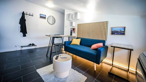 A modern living room with a blue sofa, a round coffee table, and a small side table.