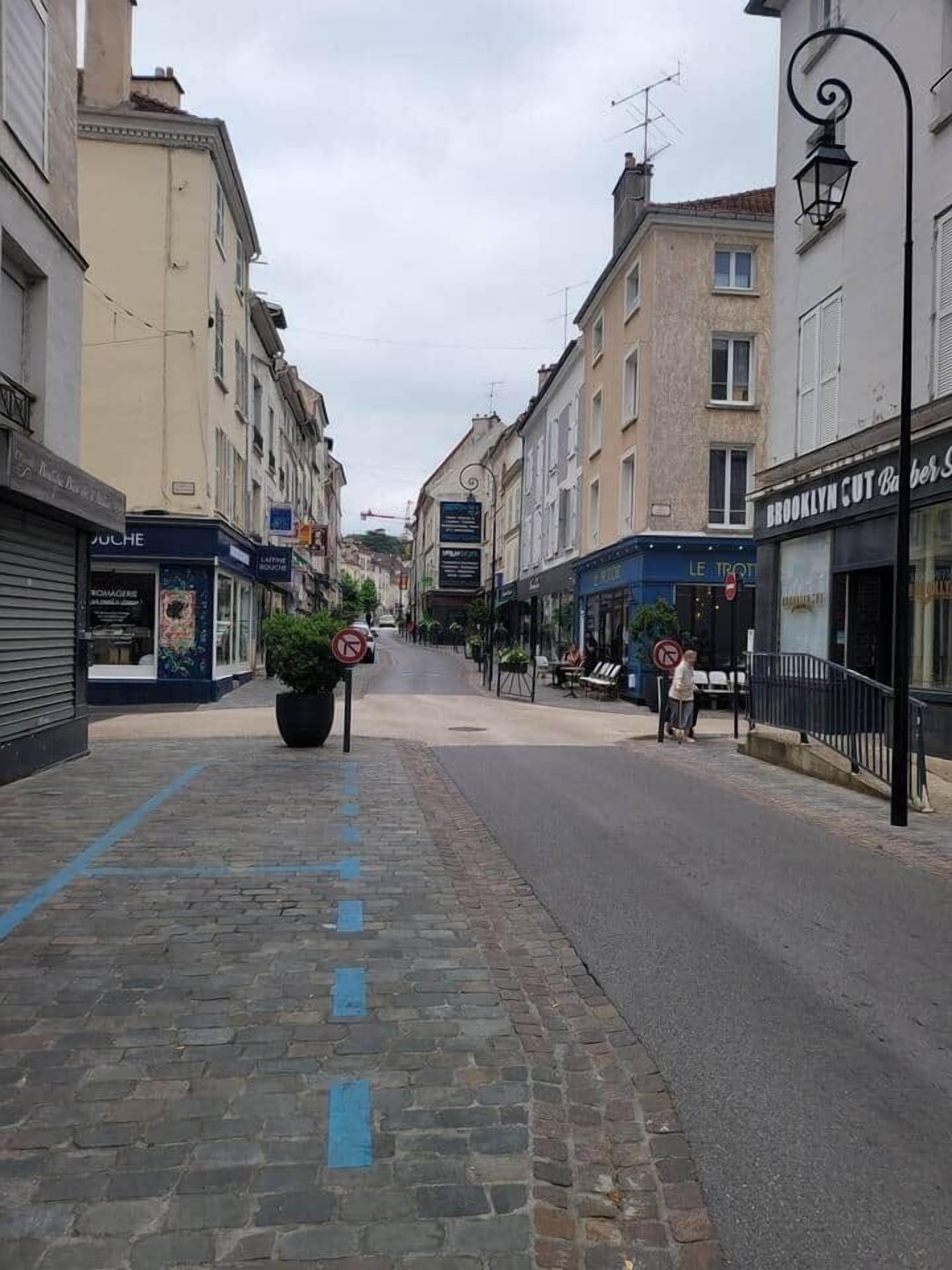 Eine Straße mit Gebäuden, einem Verbotsschild und einem Fußgänger.