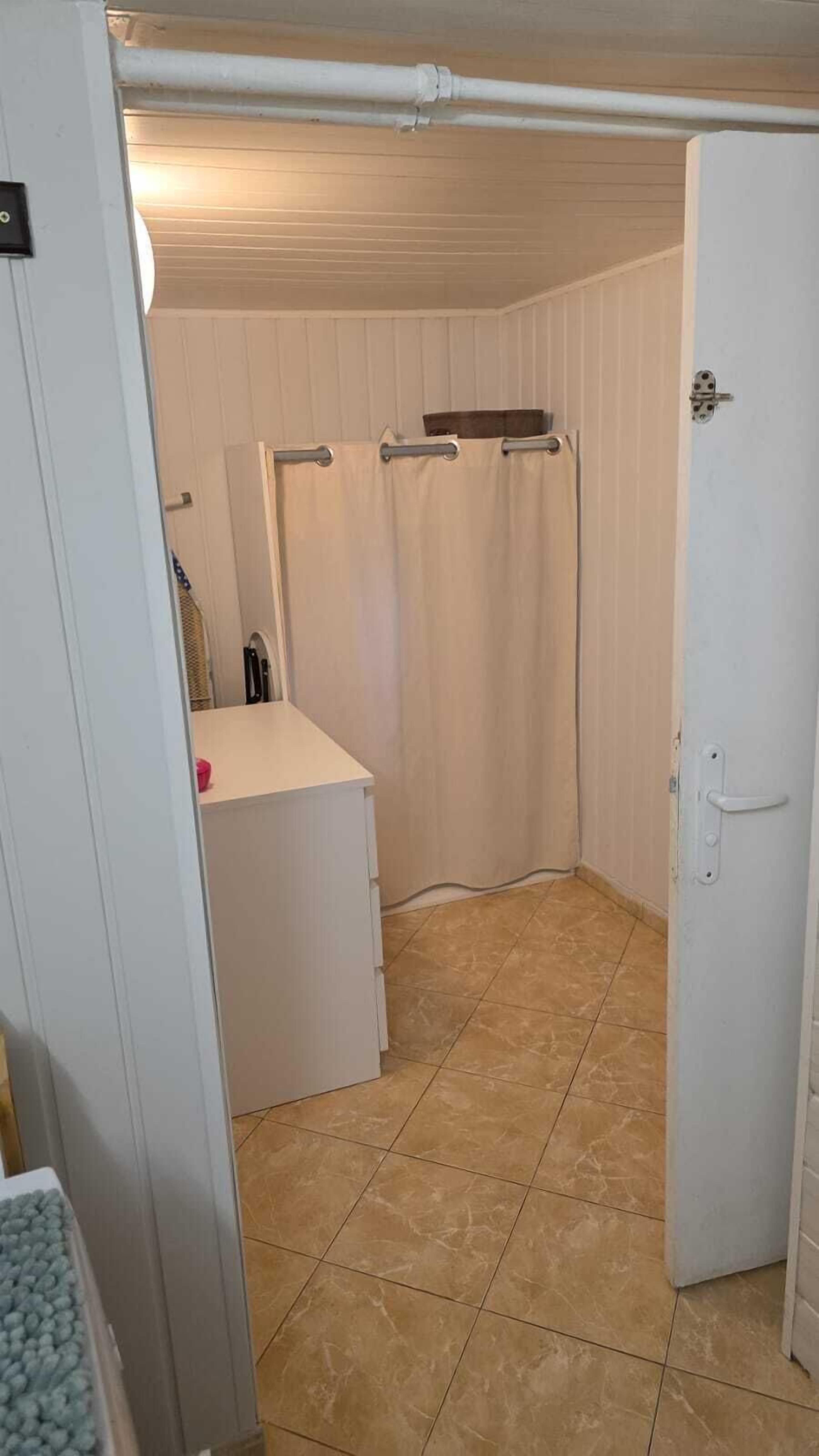 Une salle de bain avec un rideau de douche, un porte-serviettes et un lavabo blanc.