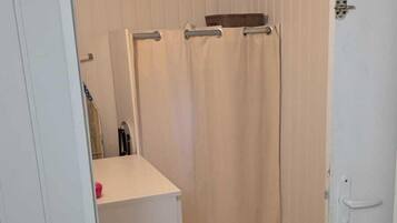 Une salle de bain avec un rideau de douche, un porte-serviettes et un lavabo blanc.