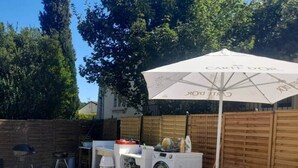 A backyard with a washing machine, a grill, a chair, and a table under an umbrella. - Quiet studio with optional access to a shared pool (La Ferté-Gaucher)