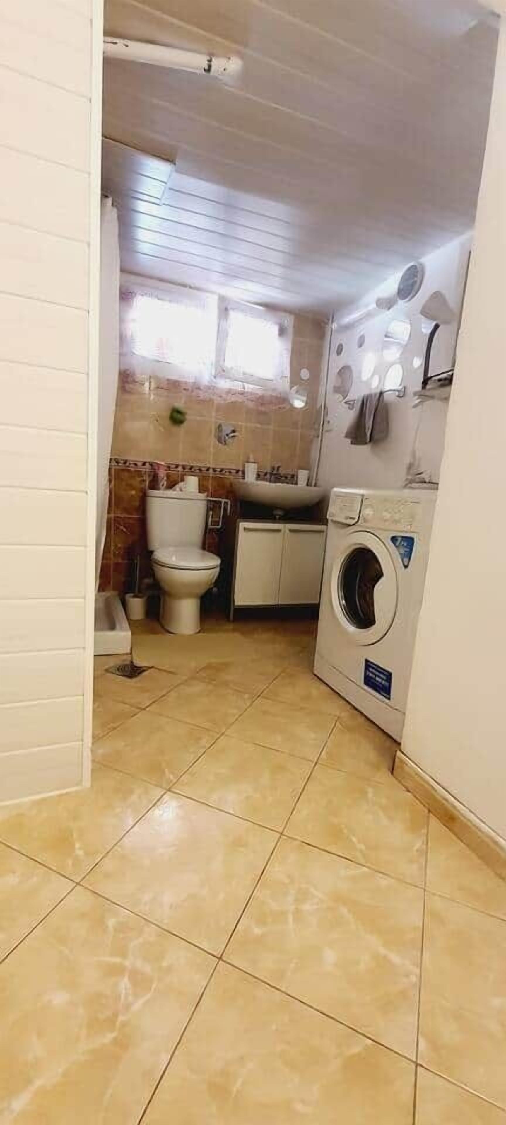 A compact bathroom with a toilet, sink, and washing machine.