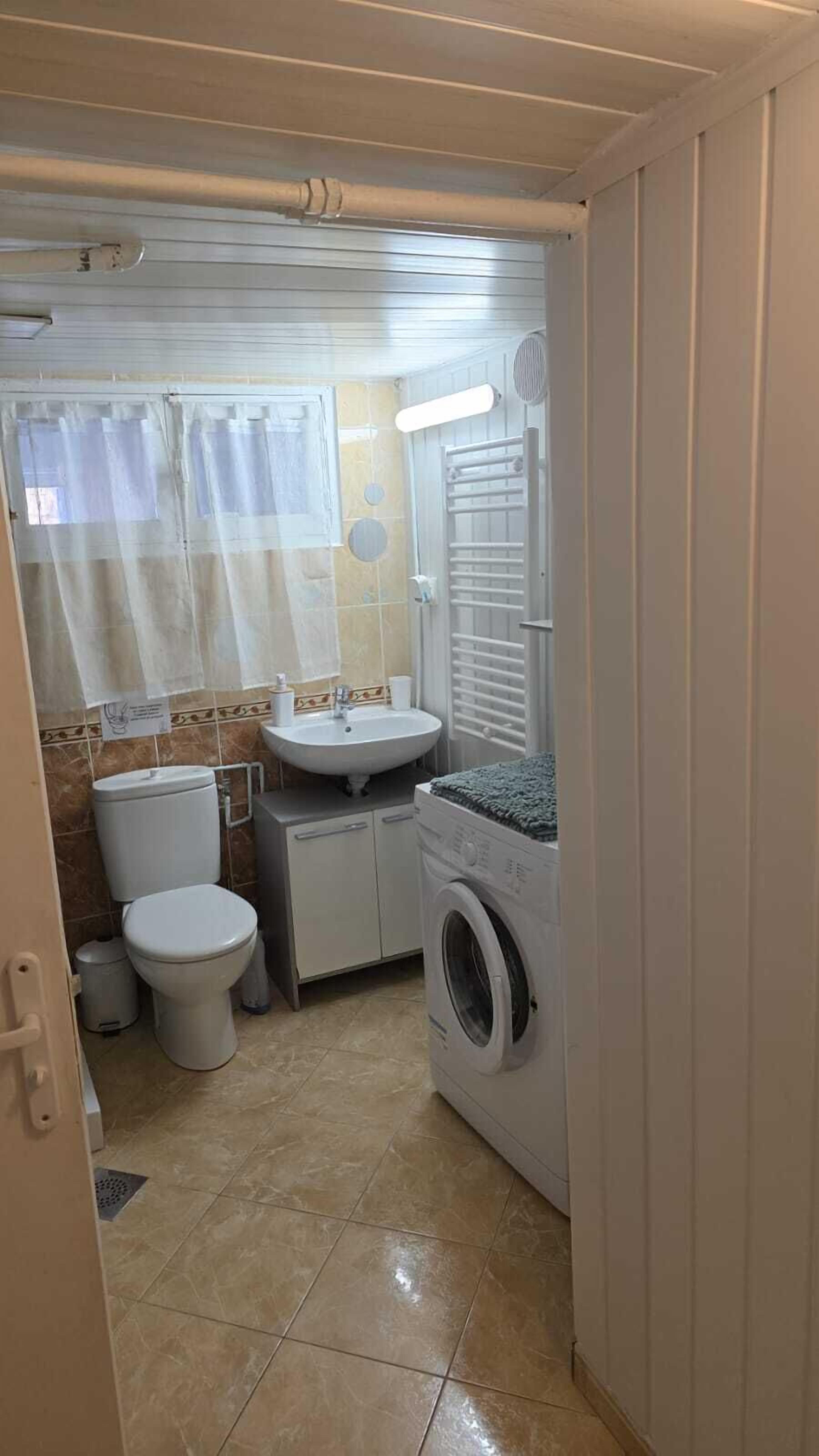 A compact bathroom with a toilet, sink, and washing machine.