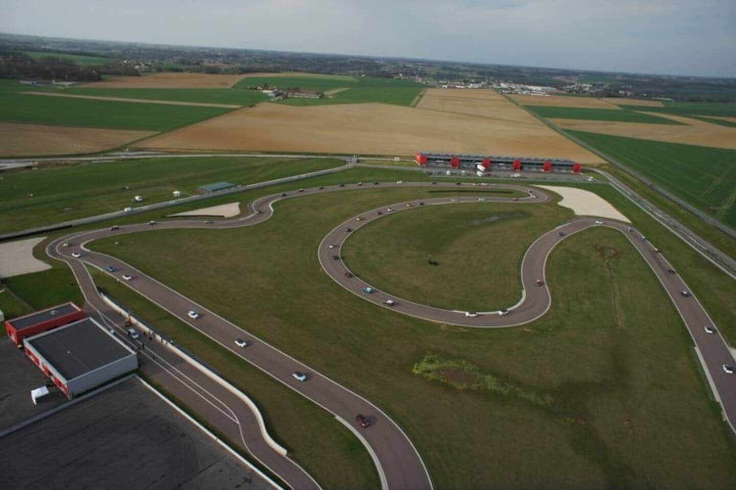 Vue aérienne d’un circuit automobile comportant de nombreux virages et quelques voitures sur la piste.