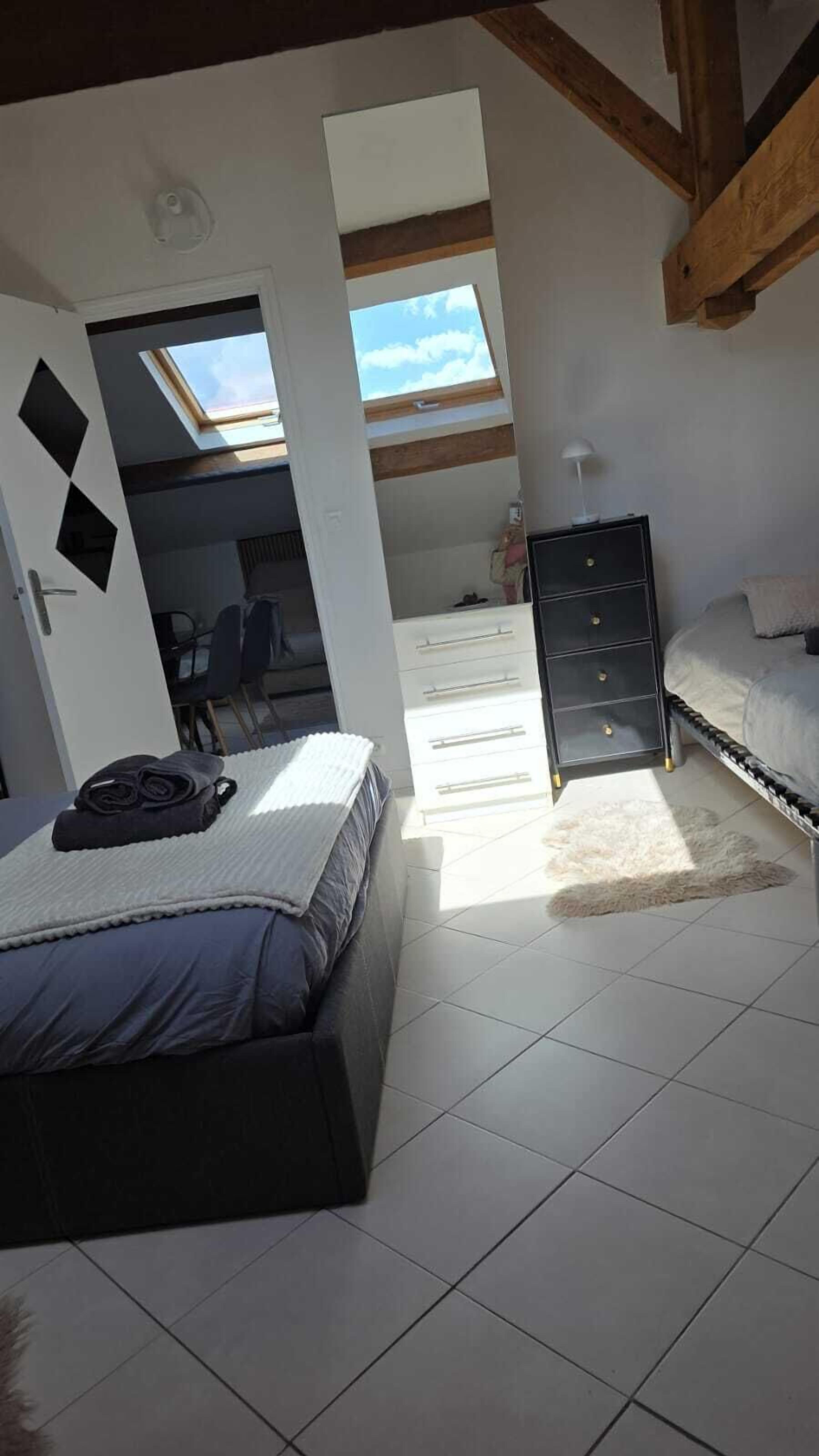 A bedroom with a bed, a dresser, a skylight, and a view of the sky.