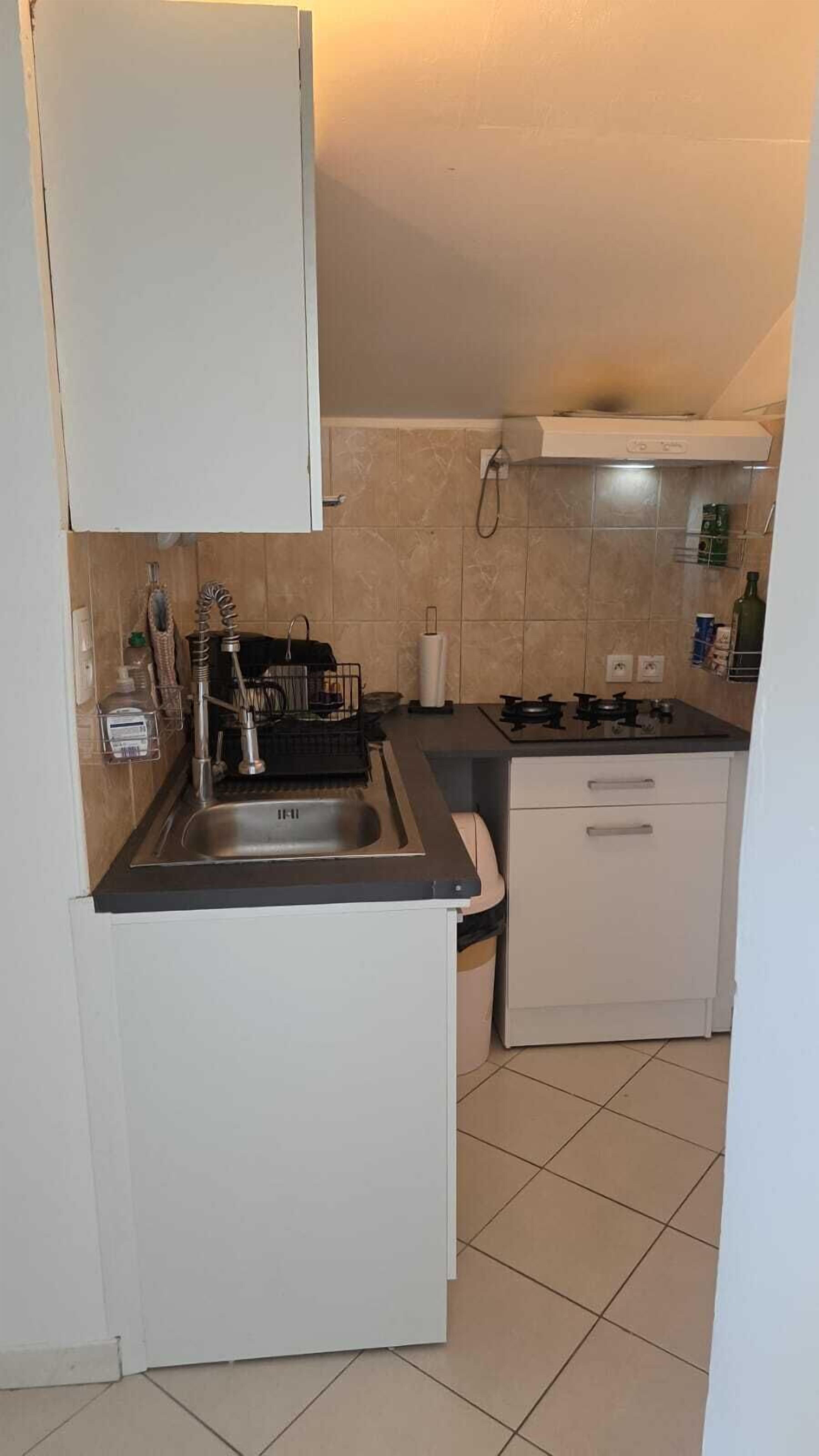 A compact kitchen with a sink, stove, and cabinets.