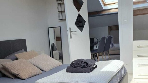 A bedroom with a bed, a door, a chair, and a view of an outdoor area.