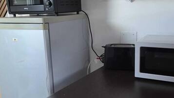 A kitchenette with a microwave, toaster, and a small refrigerator.