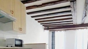 A kitchen with wooden beams, a microwave, and a refrigerator.