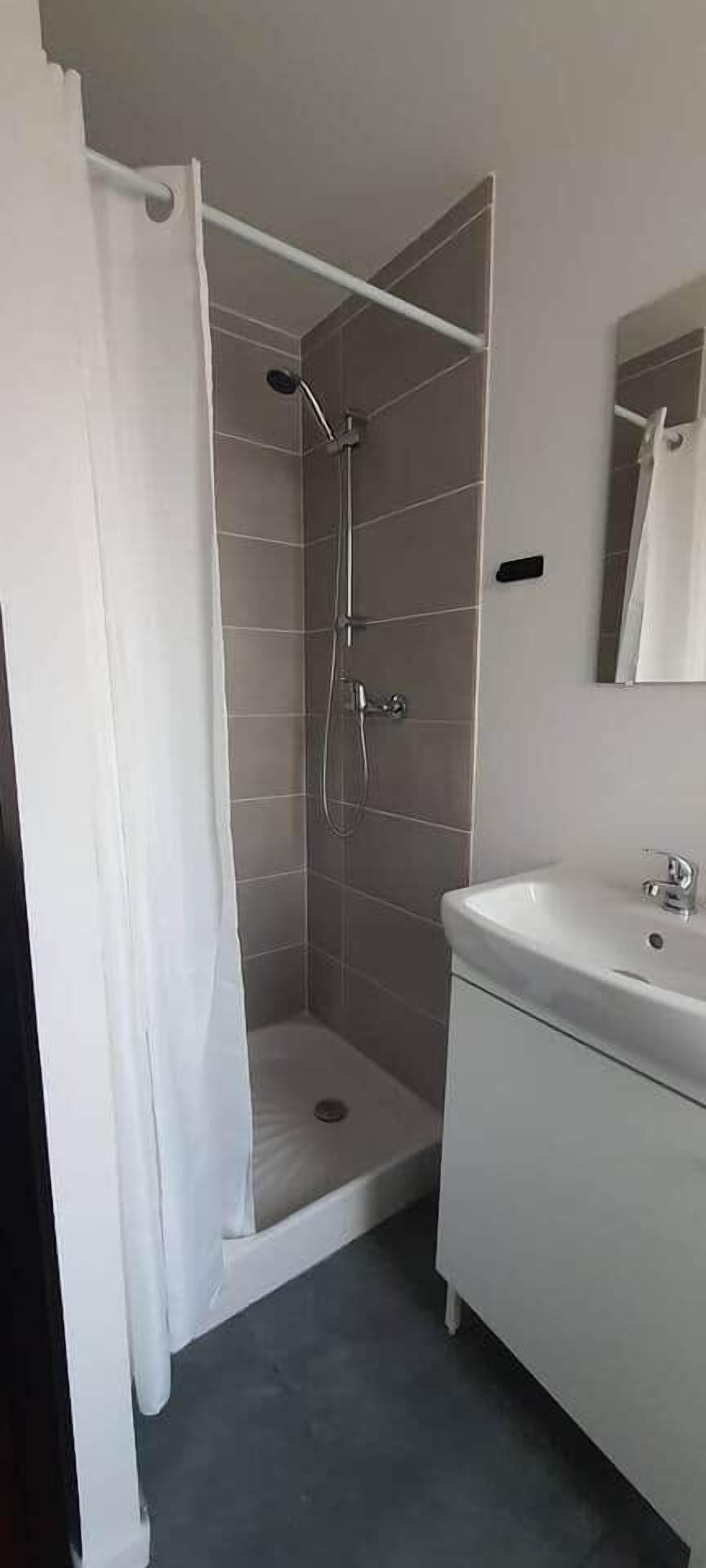 Una ducha con cortina, un lavabo y un espejo.