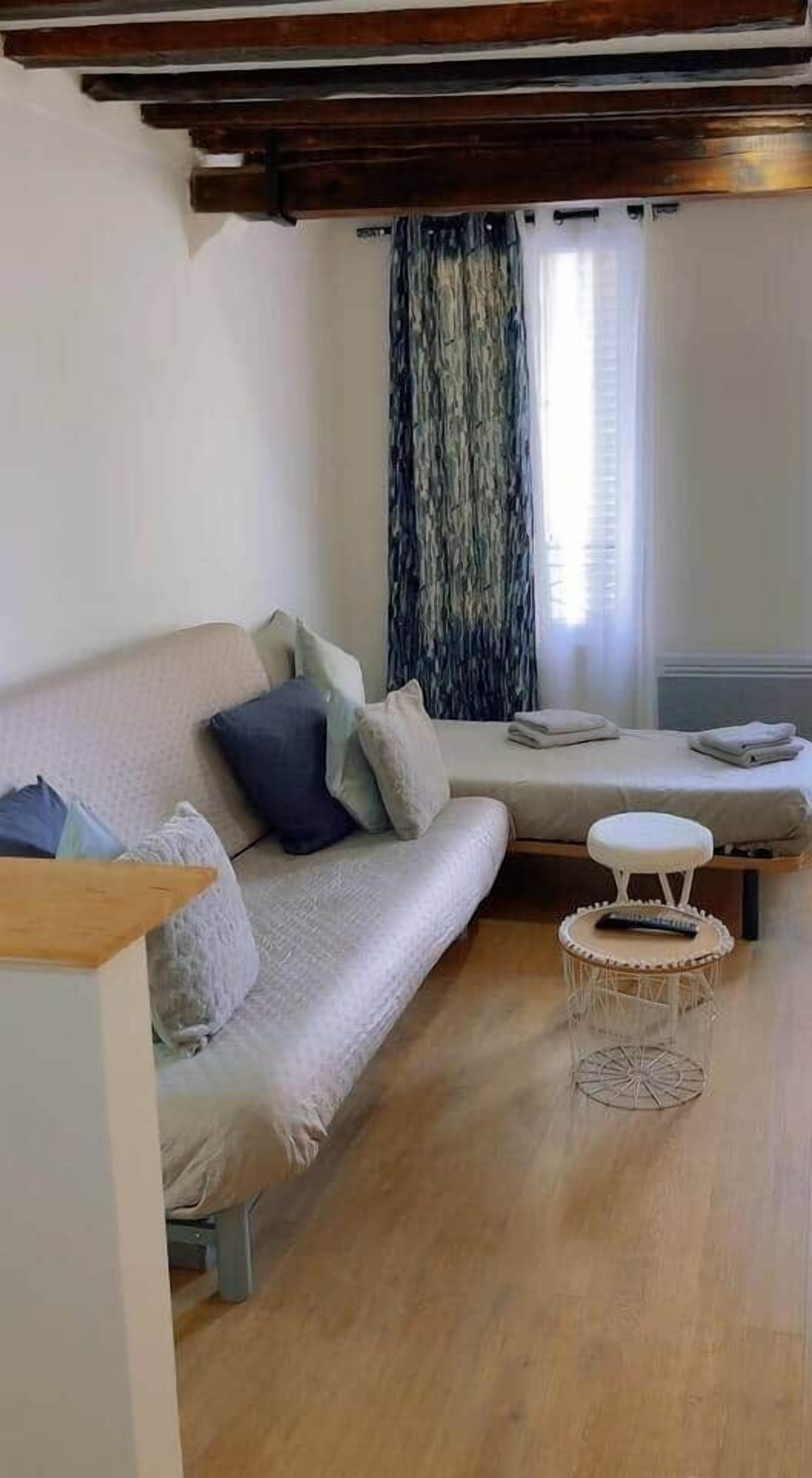 Un salon moderne avec un canapé, une petite table ronde et un lit doté d’une tête de lit.