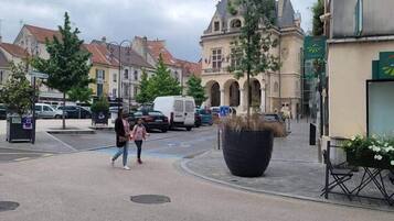 Een straat met gebouwen, een klokkentoren en een grote plantenbak.