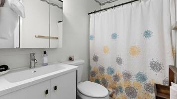 A bathroom with a white sink, a toilet, and a shower curtain with a floral pattern.