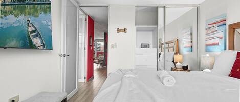 Ein Hotelzimmer mit Bett, Nachttisch, Lampe und Kunstwerk.