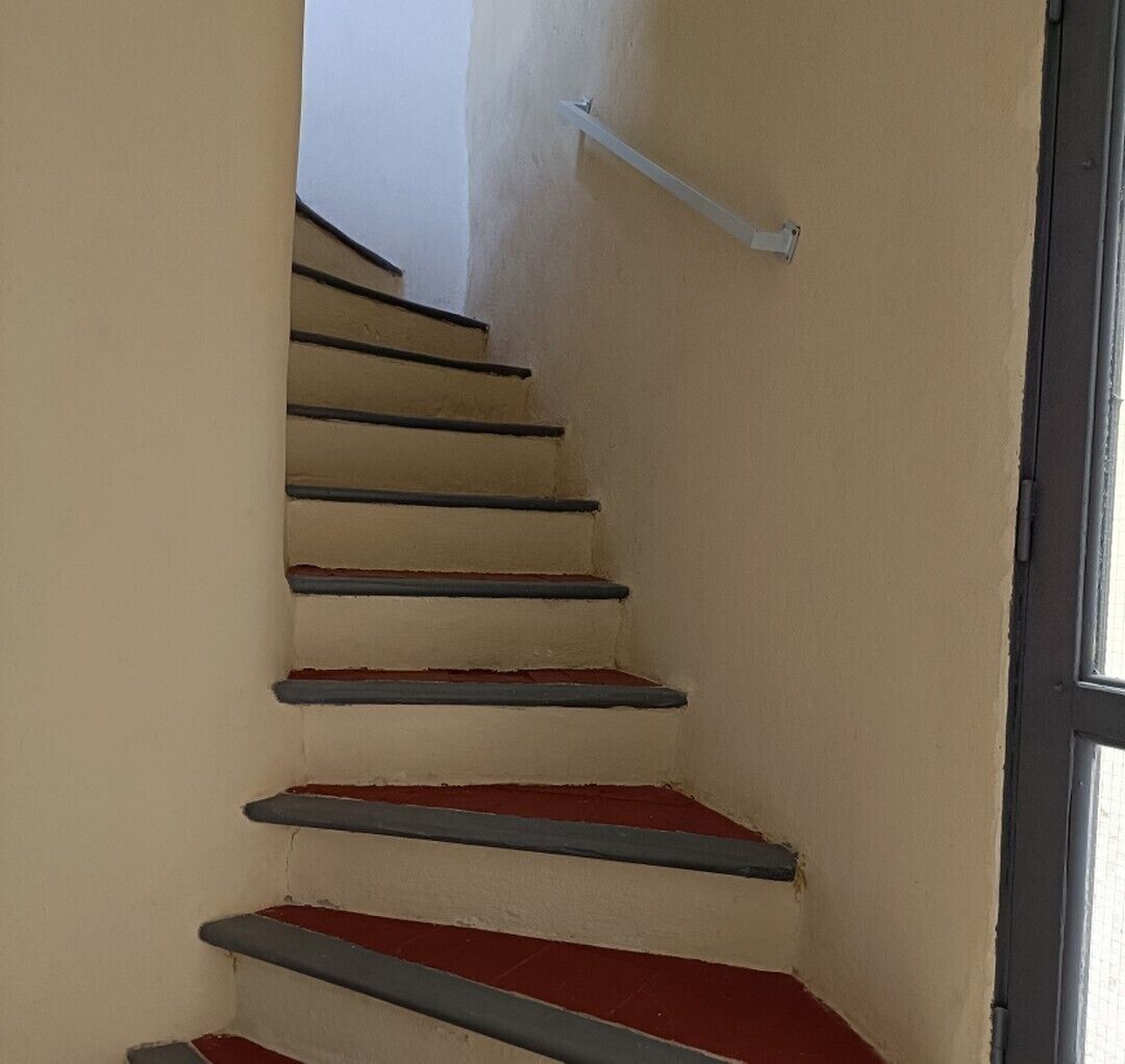 A staircase with red steps and a white handrail, leading to a door with a window.