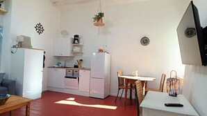 Un espace de vie compact comprenant un coin cuisine, un coin repas et un coin salon.