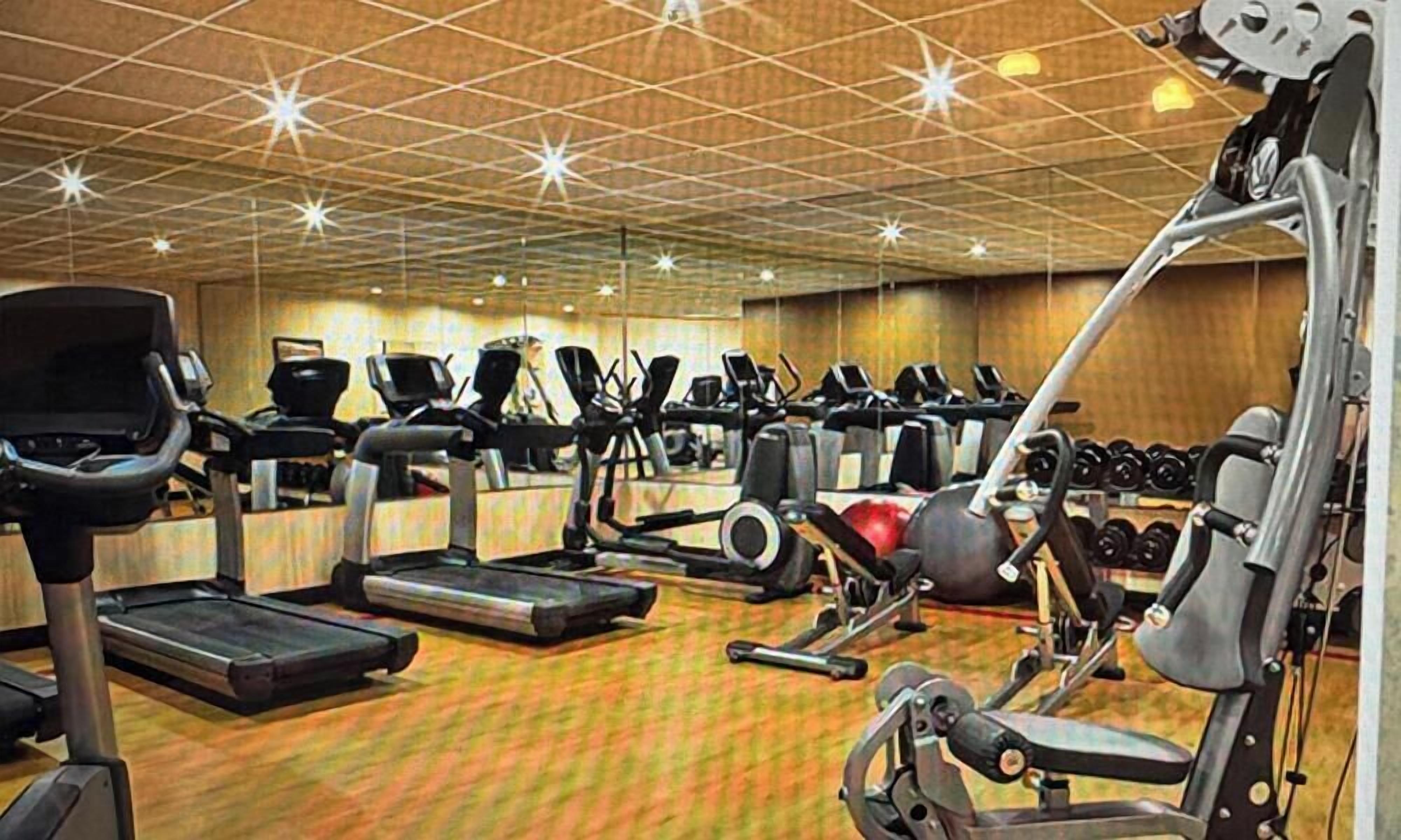 A gym with treadmills, elliptical machines, and weight equipment.