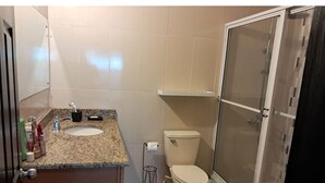 A bathroom with a granite countertop, a toilet, and a glass-enclosed shower. - 2-bedroom condo in delightful Kingston with cool AC (Kingston)