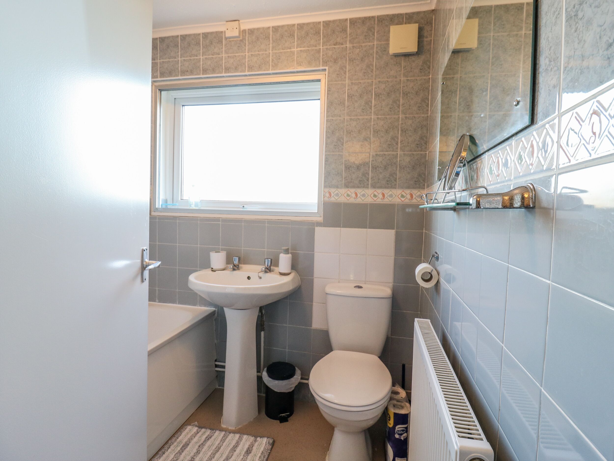 A compact bathroom with a sink, toilet, and window.