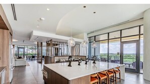 Uma cozinha ampla com uma ilha grande, eletrodomésticos modernos e vista para o exterior.