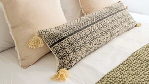 Una cama bien hecha con almohadillas estampadas y un plaid tejido.