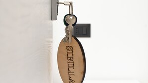 Un porte-clés avec le mot « STIBILLA » gravé, accroché à une serrure de porte.