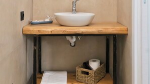 Une salle de bain avec un meuble-lavabo en bois, un lavabo blanc, un miroir et un porte-serviettes.