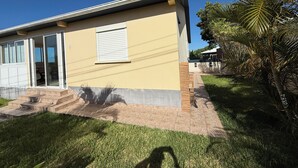 A modern house with a flat roof, a sliding glass door, and a small window with a white shutter. - Large 100 m² T3 with garden & sea view - Absolute peace and quiet in Petite-Île (Petite-Île)
