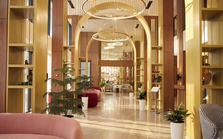 A spacious lobby with a polished marble floor, wooden bookshelves, and comfortable seating areas.